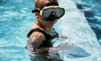 In swimming mask... Happy little girl is having fun in the pool photo