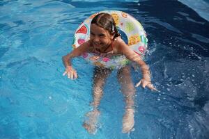With ,lifebuoy, learning how to swim. Happy little girl is having fun in the pool photo