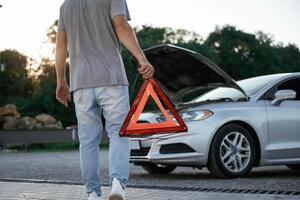Holding red sign,,, broken automobile. Man is with his car outdoors photo