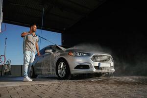 Silver, colored ,surface, washing the automobile. Man is with his car outdoors photo