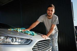 With, cloth, in hands. Car wash. Man is with automobile outdoors photo
