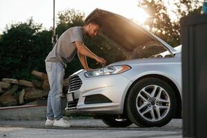 Beautiful sunlight.. Hood is opened, guy is repairing the automobile. Man is with his car outdoors photo