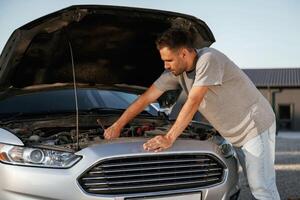 Trying to ,repair the broken automobile. Man is with his car outdoors photo