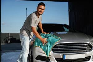 Turquoise ,cloth, polishing the vehicle. Man is with his car outdoors photo
