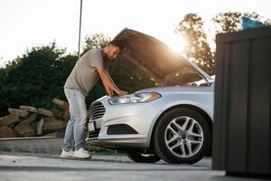 Beautiful ,,sunlight. Hood is opened, guy is repairing the automobile. Man is with his car outdoors photo