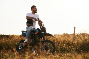 Man is,, on the motorcycle is on the field, outdoors photo