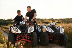 Showing how ,the, machine works. Father and daughter are with ATV outdoors photo