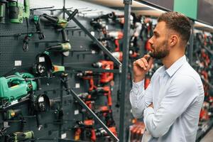 Big choice of drills. Man is in the hardware shop photo