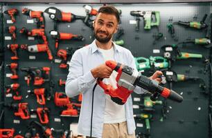 Plural perforator in hands. Man, is in the hardware shop photo