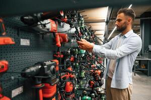 Big ,,choice of drills. Man is in the hardware ,shop photo
