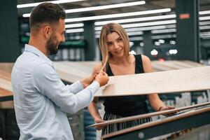 Making fun, color of parquet is the same,as girlfriend hair. Man with woman are in the hardware store photo