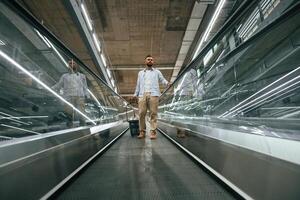 Customer is on the way.... Handsome man is on the escalator in the mall photo