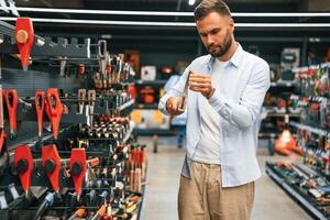 Picking an axe. Man, is ,in the hardware shop photo