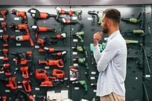 Big choice of drills.. Man is in the hardware shop photo