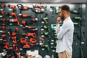 Big choice of drills,. Man is in the hardware shop photo