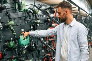 Big, choice of, drills. Man is in the hardware shop photo
