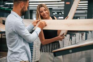 Making fun, color of parquet is,, the, same as girlfriend hair. Man with woman are in the hardware store photo