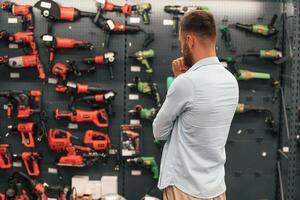 Wall with, brand new drills. Man is in the hardware shop photo