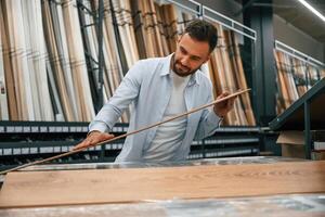Quality ,of the, wood in parquet, checking. Man is in the hardware shop photo