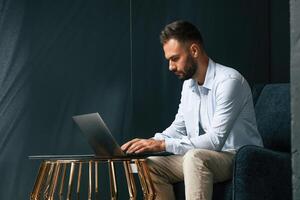 Focused, confident.. Businessman is sitting and working by using laptop photo