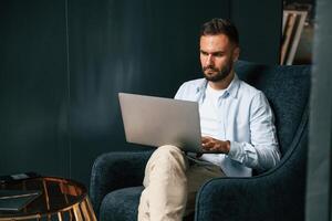 Focused,, confident. Businessman is sitting and working by using laptop photo