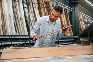 Quality ,,of the wood in parquet, checking. Man is in the hardware shop photo