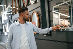 Smart, mirror, touching it. Man is in the hardware shop photo