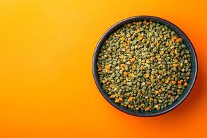 A bowl of green lentils on an orange background photo