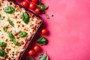 Top view of lasagna with fresh tomatoes and basil on pink background photo