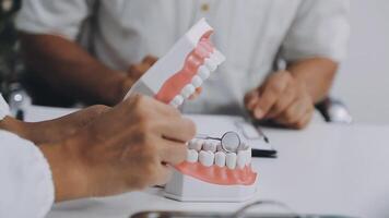 A person is holding a tooth model in front of a desk video