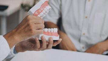 A person is holding a tooth model in front of a person video