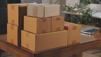 A stack of boxes on a table in front of a laptop video