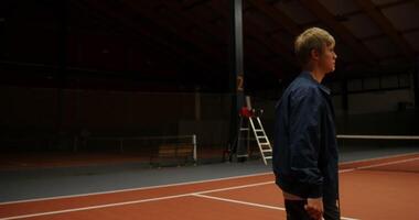 The lights turn on and a young man of European appearance with a serious look walks through the hall, carrying a basket with balls, a side view, close-up photo