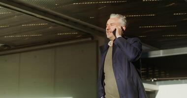 A respectable gray-haired man of European appearance, dressed in a coat, is talking on a mobile phone photo
