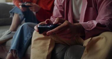A man and a woman play games while sitting on the couch at home. Close-up of male hands with a joystick, no face photo