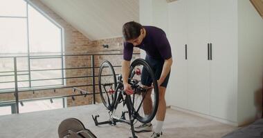 A man removes the rear wheel from a bicycle to install it on an cycling station for indoor training photo
