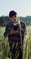 A man takes photos with a camera, standing between ears of wheat in an agricultural field on a summer sunny day. 4k vertical , red komodo