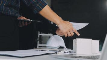 Two people are holding a piece of paper and a laptop video