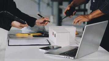 Two people working on a laptop and a paper model video