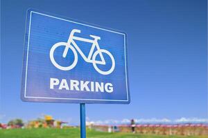 A blue traffic sign featuring a bicycle symbol against a backdrop of the sky, grass, and plants. The font is bold and easy to read, emphasizing the importance of sharing the road with bicyclists photo