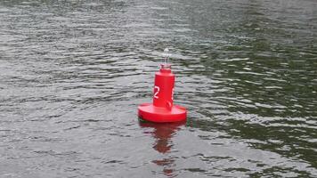 A vibrant red buoy marked clearly with a number floats steadily and securely on the surface of the tranquil water video