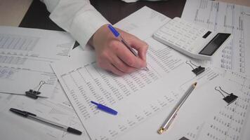 A professional examining financial data on papers with a calculator, showcasing meticulous analysis. video