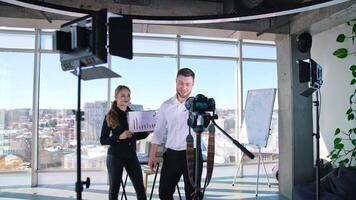 Young business people recording . Handsome guy talking on camera inviting to join the project. Creative bloggers man and woman speaking on professional camera in studio. video