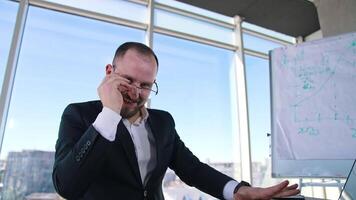 Funny man in suit typing on a laptop. Mad businessman in glasses working on a computer nervously in office room. video