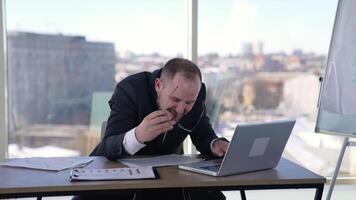 Man doing funny faces sitting in front of laptop. Mad businessman typing nervously with fingers on keyboard and looking to the sides. Entrepreneur with insane face in office. video