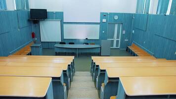 Empty auditorium. Modern lecture hall in the university. Wooden desks in front of blackboard and multimedia board in conference hall. video