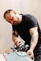 Construction Worker Using Tile Saw cutting Ceramic Tiles on table photo
