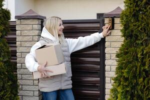 Delivery woman waving while holding cardboard boxes and wearing sunglasses photo