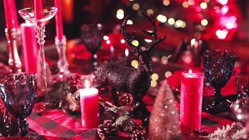 Shiny deer toy decoration on a festive table at Christmas. Beautifully decorated table with candles and glasses for Christmas celebration. Festive mood. video