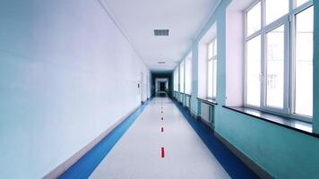 Motion along the corridor inside empty college. Blue long hallway with big windows in modern university. video